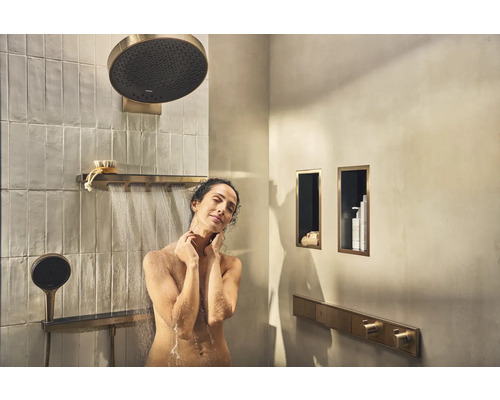 Frau unter der Dusche mit Kopfbrause und Handbrause im Badezimmer