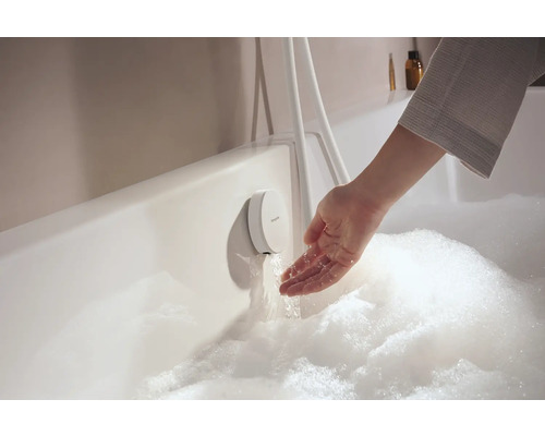 Hand prüft das Wasser aus einem Unterputz-Badewannenarmatur in einer mit Schaum gefüllten Badewanne