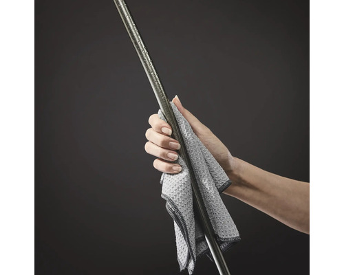 Eine Hand wischt eine Metallstange mit einem Tuch ab.