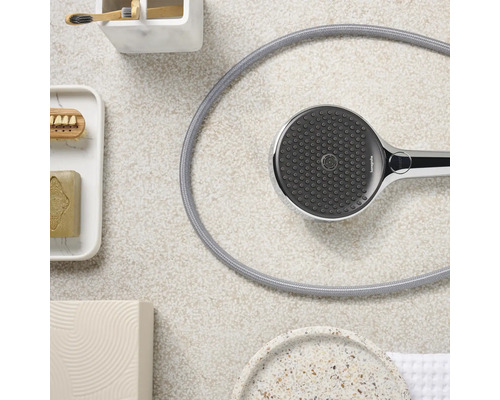 Douchette avec flexible et accessoires de salle de bains sur fond clair