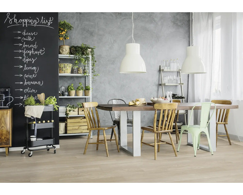 Cuisine lumineuse avec table à manger, chaises, étagère et tableau noir pour liste de courses.
