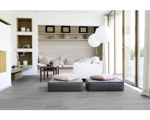 Salon lumineux avec sol gris, coussins de siège, canapé et étagères