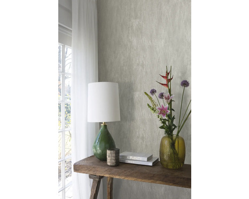 Dekoratives Interieur mit gemusterter Tapete, Tischleuchte, Blumen und Büchern auf einem Holztisch