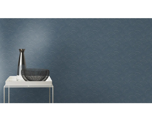 Nahaufnahme einer blauen Wandtapete mit einem sich wiederholenden, halbkreisförmigen Muster, zusammen mit einer Vase und einer Schale auf einem Tisch.