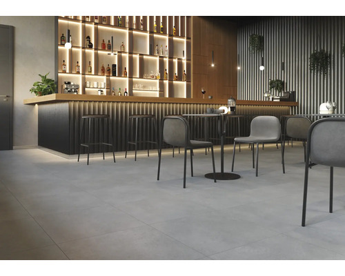 Intérieur avec bar, tabourets de bar, tables et chaises sur un sol carrelé.