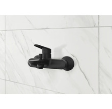 Robinet de douche noir sur un mur de marbre blanc