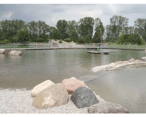 Lac de baignade naturel avec ponton en bois, rive plantée et pierres dans l''eau