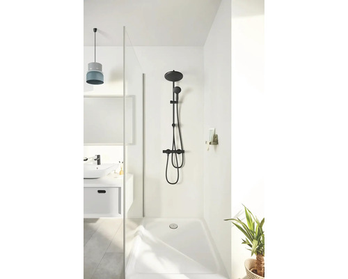 Espace douche avec robinetterie de douche noire, pomme de douche et douchette à main devant un mur blanc