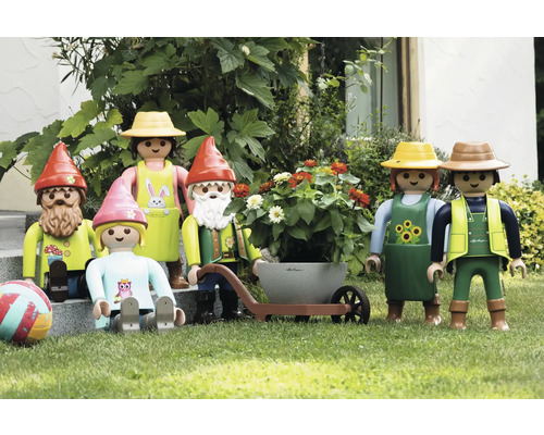 Scène de jardin avec des figurines Playmobil, comprenant des nains de jardin et des jardiniers avec une brouette et une jardinière