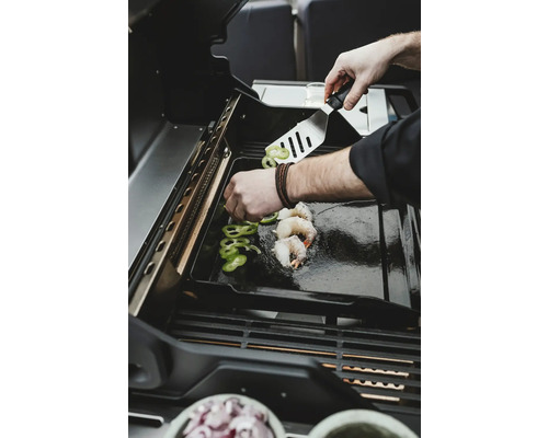 Auf einem Grill werden Garnelen und Paprika zubereitet.