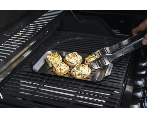 Gefüllte Champignons auf einer Grillplatte mit Grillzange auf einem Grill