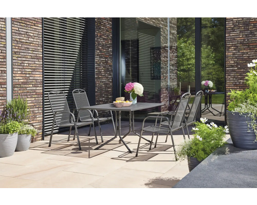 Gartenszene mit Tisch, Stühlen und Pflanzen auf einer Terrasse vor einer Hauswand
