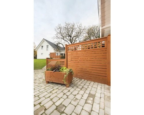 Scène de jardin avec clôture en bois, jardinière et pavage en pierre