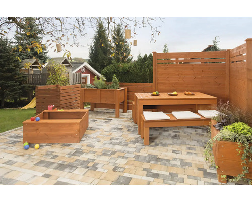 Scène de jardin avec terrasse en bois, coin salon avec table et bancs, jardinière surélevée et bac à sable