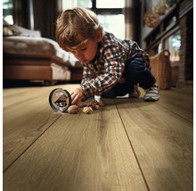 Un enfant joue avec des noix sur un plancher en bois dans le salon
