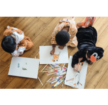 Trois enfants en costumes d''animaux dessinent par terre avec des feutres sur du papier.