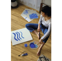 Une femme est assise sur un sol stratifié et peint avec de la peinture bleue.