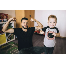Un père et son fils montrent leurs muscles dans la chambre d''enfants