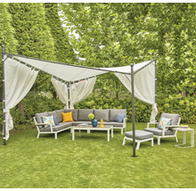 Salon de jardin sous un pavillon avec rideaux sur une pelouse.