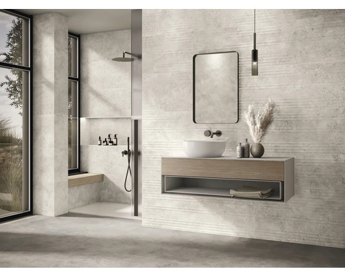 Salle de bains moderne avec lavabo, miroir, douche et carrelage aspect pierre pour une ambiance élégante.