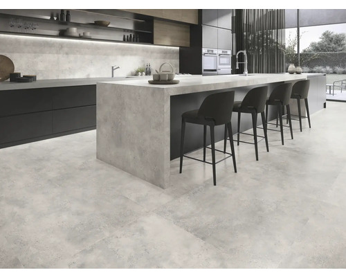 Cuisine moderne avec carrelage au sol aspect béton, îlot de cuisine et tabourets de bar.