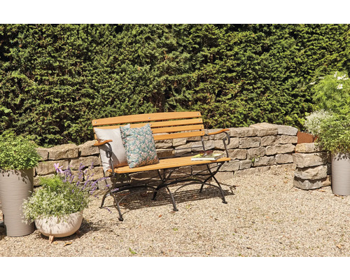 Banc de jardin en bois avec coussins et livre dans un décor de jardin