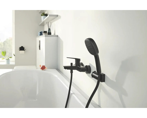 Salle de bains avec robinetterie noire et douchette sur le mur au-dessus de la baignoire.