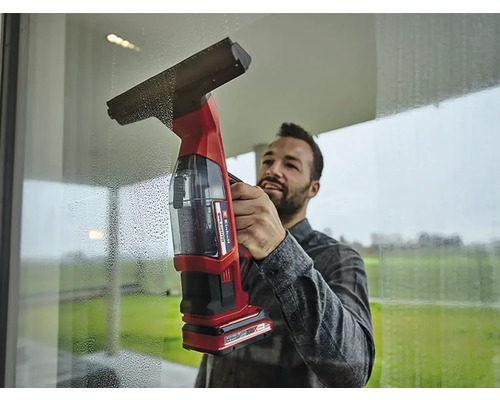 Mann reinigt Fenster mit einem Akku-Fenstersauger.