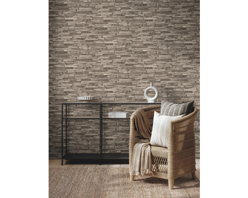 Salon avec papier peint aspect pierre, étagère et fauteuil en rotin