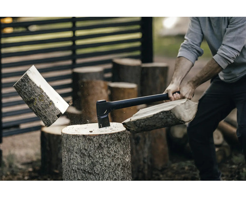 Un homme coupe du bois avec une hache sur un billot