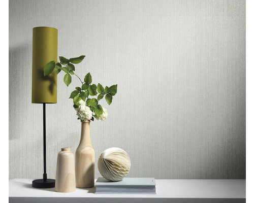 Szene mit Tapete, Lampe, Vasen und Dekorationsgegenständen auf einem Tisch.