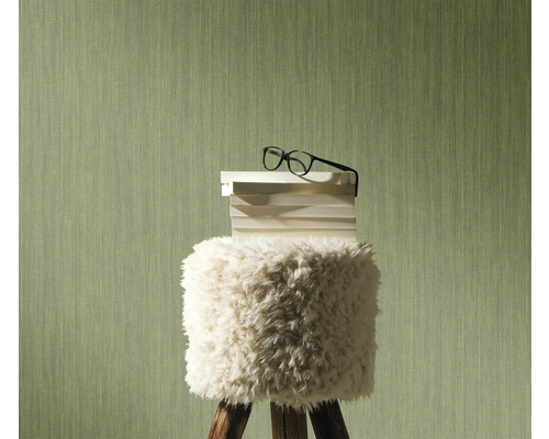 Scène décorative avec un tabouret sur lequel reposent des livres et des lunettes, devant un mur structuré