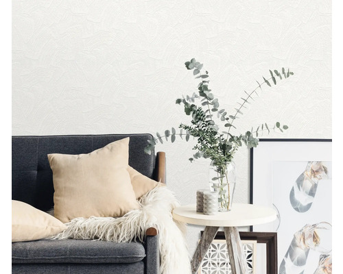 Scène de salon avec canapé gris, coussins, table, vase avec des plantes et revêtement mural