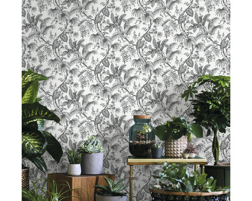 Szene mit gemusterter Tapete mit Pflanzenmotiven und verschiedenen Zimmerpflanzen auf Möbeln.