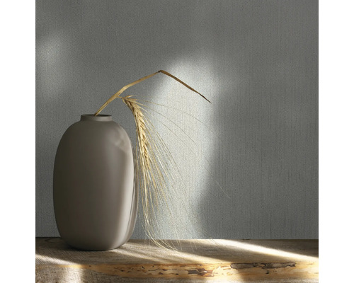 Dekorative Tapete mit Textilmuster und Vase mit Getreideähre auf einem Holztisch.