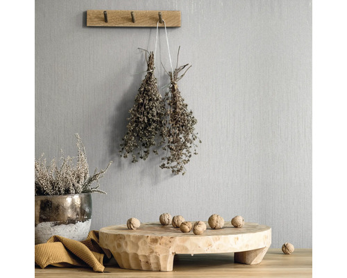 Dekorative Szene mit Holzelementen, Kräutern und Nüssen vor einer strukturierten Wand