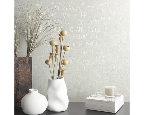 Intérieur décoratif avec vases, fleurs séchées, livre et bougie devant un mur avec un motif d''écriture