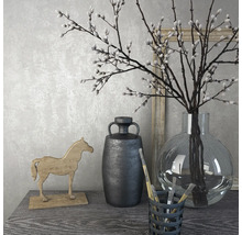 Dekoratives Stillleben mit Vase, Zweigen, Holzpferd und Krug auf einem Tisch.