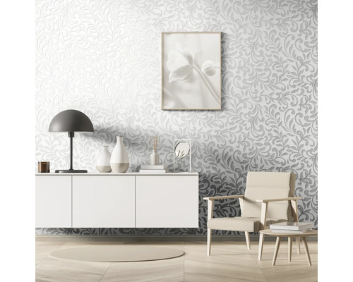 Wohnzimmer mit Relief Tapete, Kommode, Lampe, Sessel und Dekoartikeln.