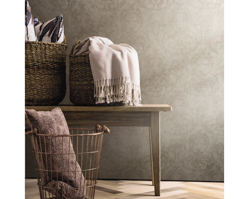 Dekorative Körbe und Textilien auf einem Holztisch vor einer gemusterten Tapete