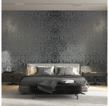 Schlafzimmer mit floral gemusterter Tapete hinter dem Bett
