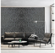 Wohnzimmer mit grauer, gemusterter Tapete, Sofa, Sessel und Couchtischen