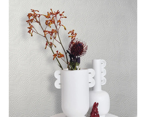 Helle Tapete mit Wellenmuster, dazu weiße Vasen und Blumen