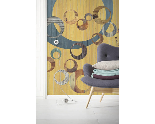 Papier peint intissé jaune avec motif de cercle et un fauteuil dans la pièce.