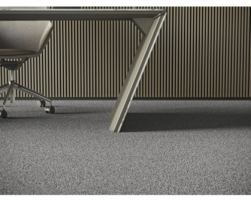 Vue détaillée d''un revêtement de sol en moquette grise dans un bureau avec un bureau et une chaise de bureau.