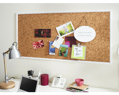 Espace de travail avec mur en liège, photos, notes et fournitures de bureau.