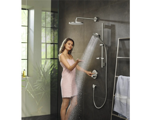 Frau testet Duschsystem mit Kopfbrause und Handbrause im Badezimmer.