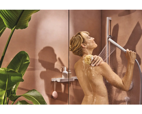 Frau unter der Dusche mit Handbrause und Schwamm.