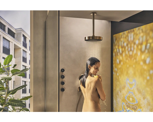 Frau unter einer Regendusche mit Deckenmontage in einem modernen Badezimmer.