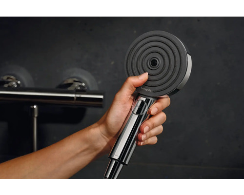 Eine Hand hält einen Handbrausekopf der Marke Hansgrohe.